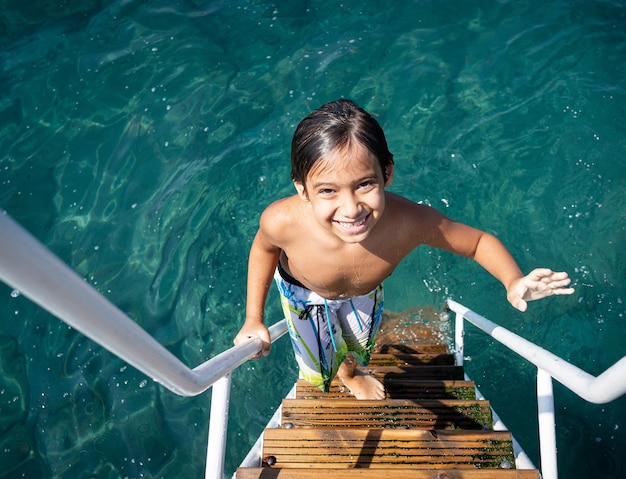 Niño escalada en el muelle del mar