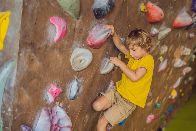 Niño escalando una pared de roca con botas especiales para interiores