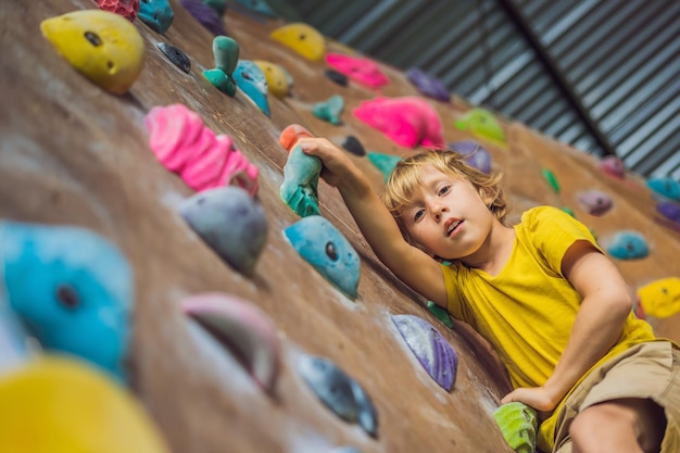 Niño escalando una pared de roca con botas especiales para interiores