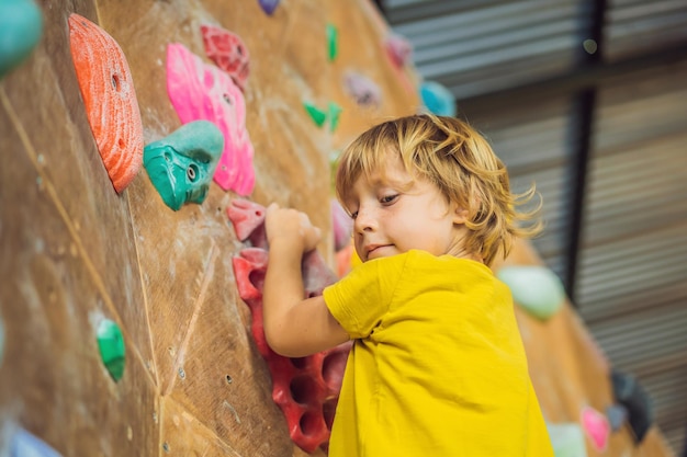 Niño escalando una pared de roca con botas especiales para interiores