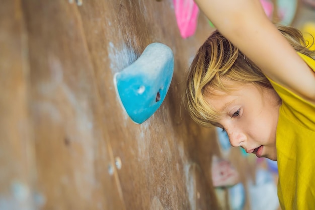 Niño escalando una pared de roca con botas especiales para interiores