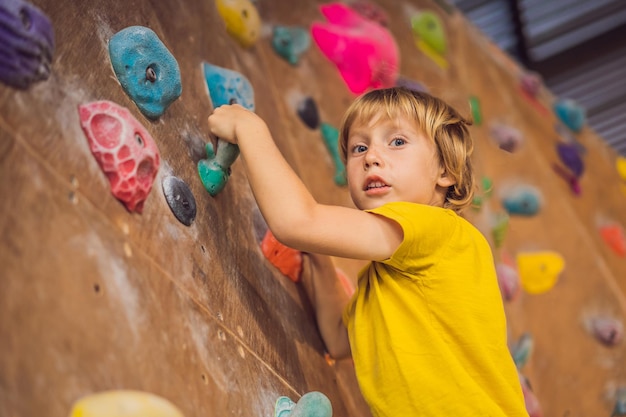 Niño escalando una pared de roca con botas especiales para interiores