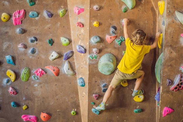 Niño escalando una pared de roca con botas especiales para interiores