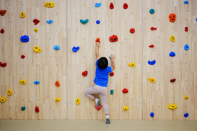 Niño escalando una pared de roca interior