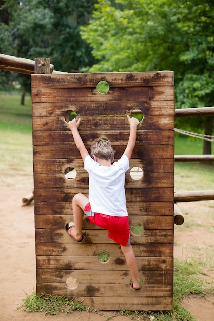 Niño escalando en un paseo en el parque infantil