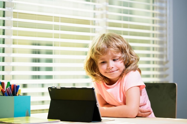 Niño escolarización en casa escuela en línea colegial haciendo su tarea con tableta digital en casa niño nosotros