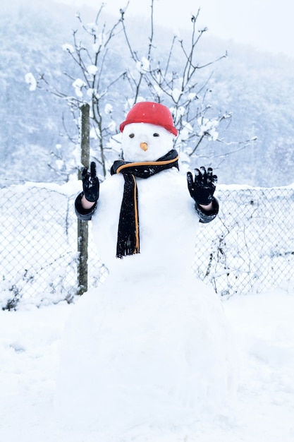 Niño escondido detrás de un muñeco de nieve, divertidas actividades de invierno