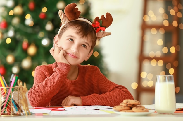 Niño escribiendo una carta a Santa en casa en la víspera de Navidad