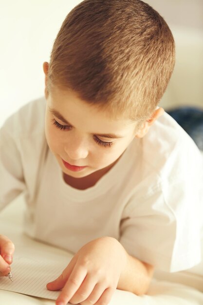 Niño escribiendo en un cuaderno en un sofá en casa