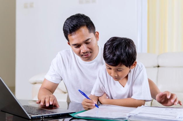 Niño escribiendo en un libro de texto con su padre