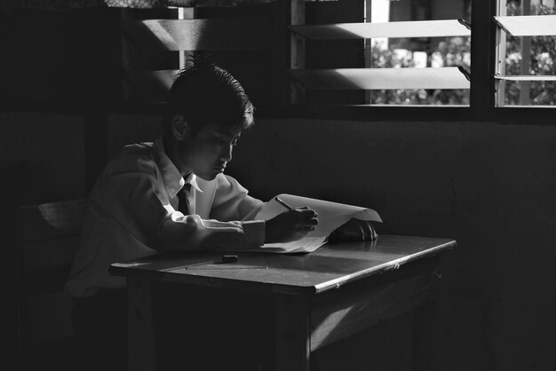 Niño escribiendo mientras está sentado en el aula