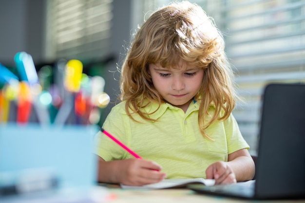 Niño escribiendo la tarea en la clase de la escuela Un niño en edad escolar hace la tarea en casa Retrato de un niño pequeño sentado en la mesa haciendo la tarea Niño inteligente haciendo ejercicios de lógica solo en casa