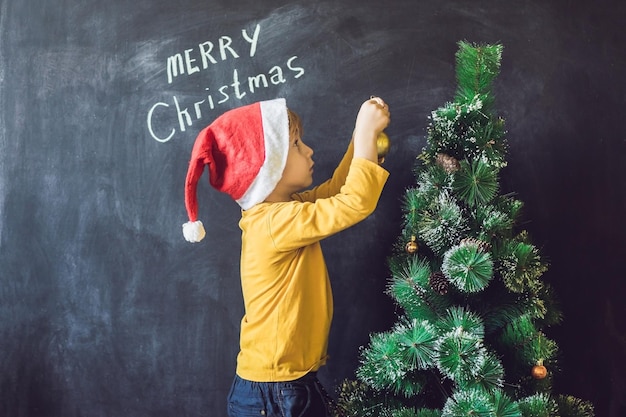 El niño escribió una inscripción Feliz Navidad. Árbol de Navidad. Navidad infantil y vacaciones de año nuevo.