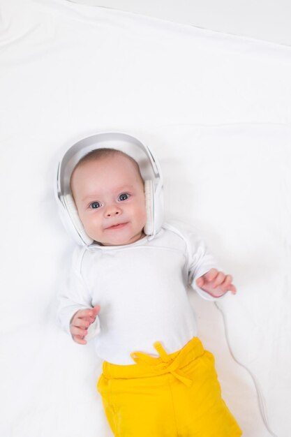 El niño escucha música con auriculares en un fondo blanco.