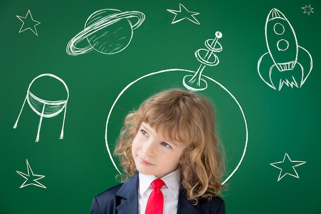 Niño de la escuela en clase. Niño feliz contra la pizarra verde. Concepto de educación