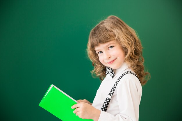 Niño de la escuela en clase. Niño feliz contra la pizarra verde. Concepto de educación