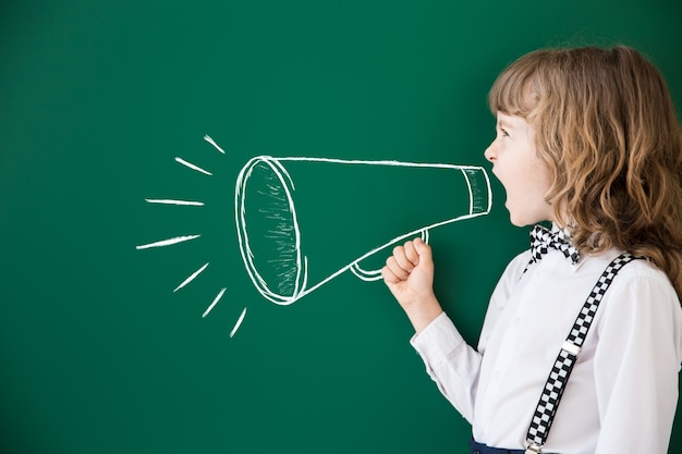 Niño de la escuela en clase. Niño feliz contra la pizarra verde. Concepto de educación