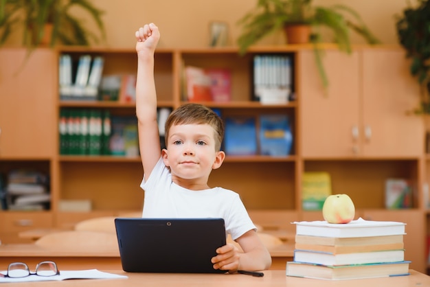 Niño de escuela con computación de tableta en el aula