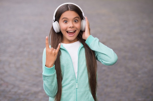 Niño de escuela divertido escuchar música o libros de audio en auriculares para la educación y la alegría, la vida moderna y la diversión.