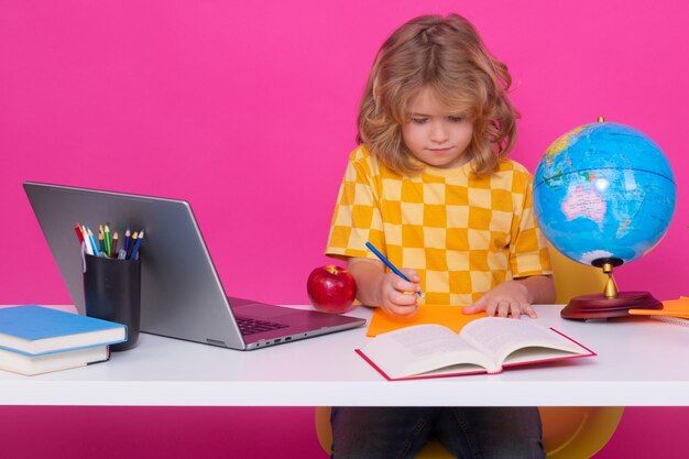Niño de escuela estudiando en un aula de escuela primaria Niño estudiando en una lección en un fondo rojo rosado aislado