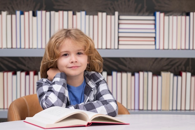 Niño de la escuela estudiando en la biblioteca de la escuela Retrato de niño leyendo en la biblioteca en el fondo con libros