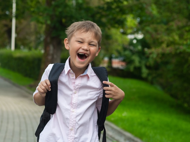 Niño de escuela feliz sosteniendo su bolso y sonriendo