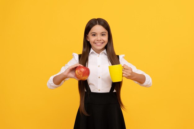 Niño de escuela feliz en uniforme mantenga sed de manzana y botella de agua