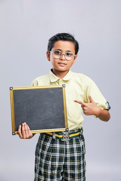 Niño de la escuela india mostrando tablero negro con espacio de copia