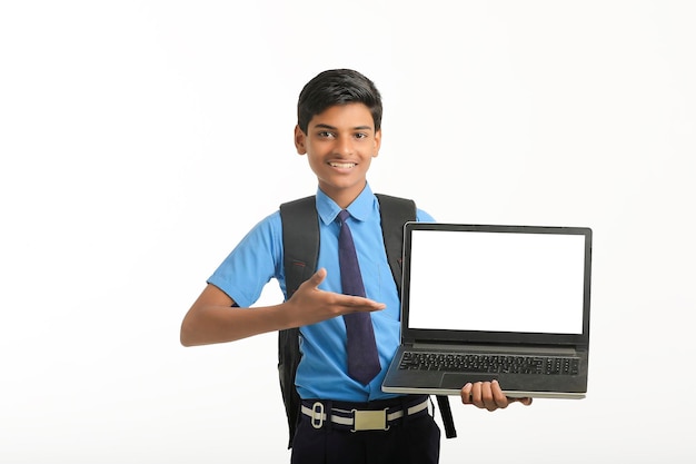 Niño de la escuela india que muestra la pantalla del portátil sobre fondo blanco.