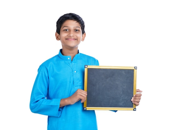 Niño de la escuela india que muestra la pizarra en blanco sobre fondo blanco.