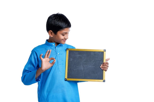 Niño de la escuela india que muestra la pizarra en blanco sobre fondo blanco.