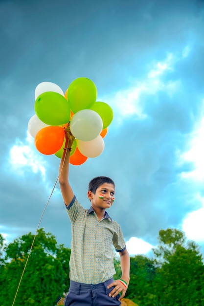 Niño de escuela indio saltando en el cielo con globos de tres colores y celebrando el día de la independencia o la República de la India