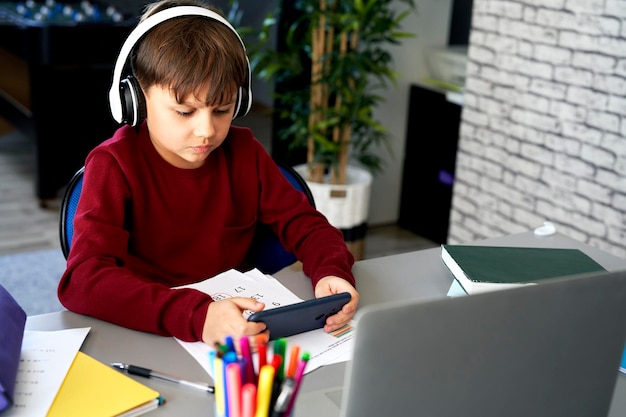 Niño de escuela jugando al teléfono durante la educación en casa