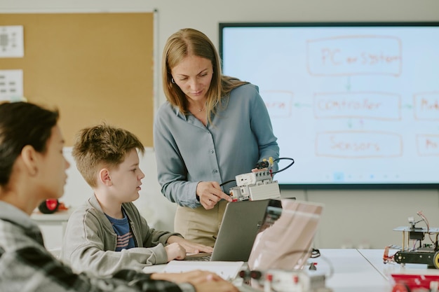 Niño de escuela mirando al robot en manos de la maestra