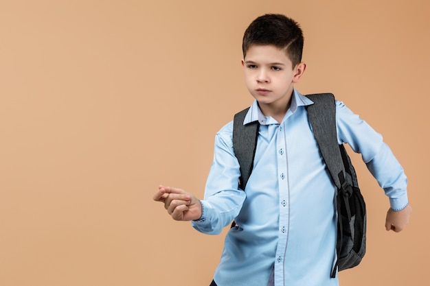Un niño de escuela con una mochila gris.