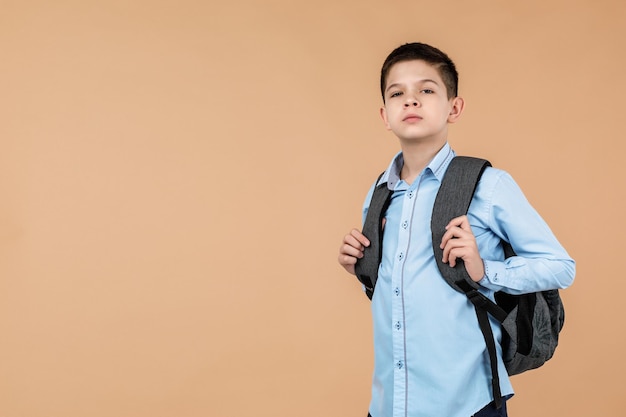 Un niño de escuela con una mochila gris.