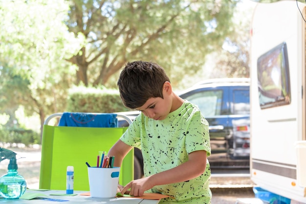 Niño de escuela primaria haciendo trabajo manual mientras está de vacaciones y preparándose para volver a la escuela