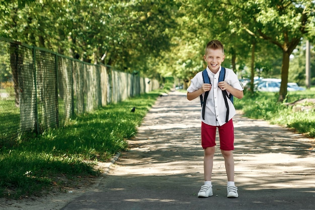 Un niño de una escuela primaria con una mochila en la calle.