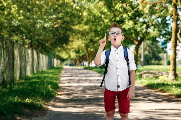 Un niño de una escuela primaria con una mochila en la calle.