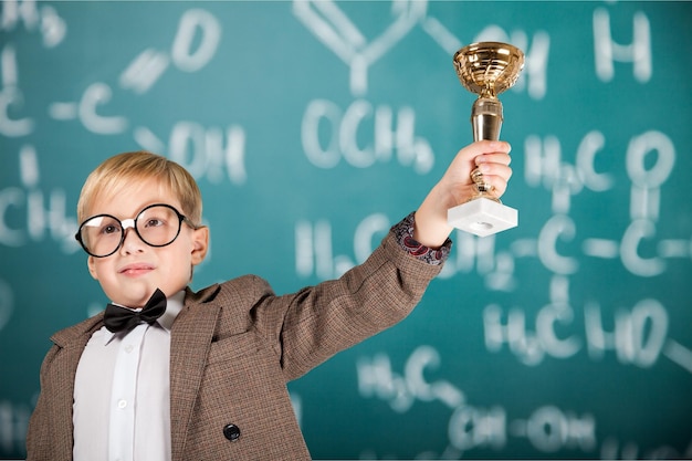 niño de escuela primaria recibiendo un trofeo en el aula con profesores y compañeros de clase