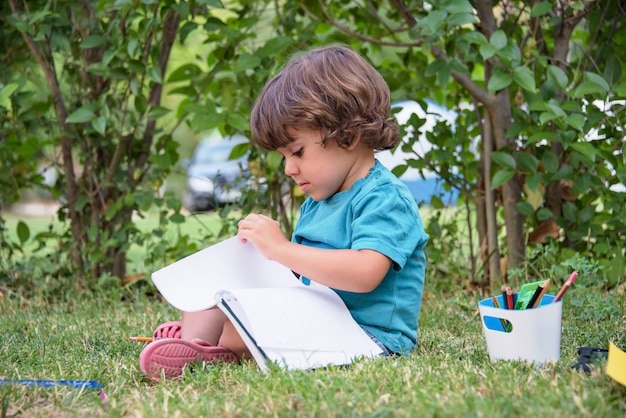 Niño de escuela primaria tirado en la hierba haciendo la tarea