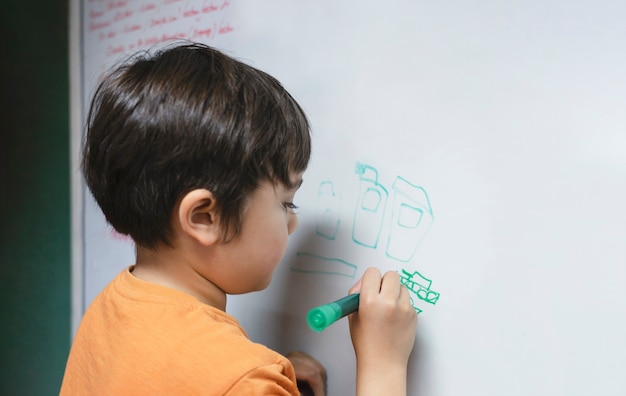 Niño de la escuela de retrato dibujo tanque de dibujos animados en la pizarra, niño niño con lápiz de color escribir a bordo, educación en el hogar, concepto de educación