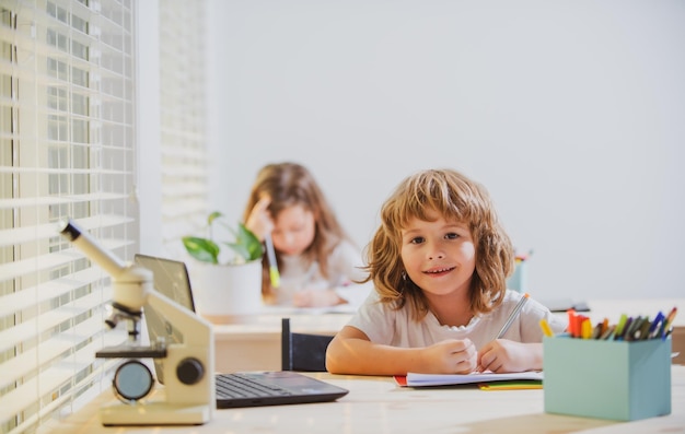 Niño de escuela sentado en la mesa escribiendo deberes o preparándose para el examen Estudio de niños Pequeño aprendizaje de estudiantes