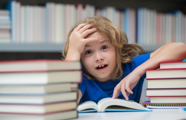 Niño de escuela sorprendido en la biblioteca de la escuela libro de lectura infantil en la escuela alumno nerd estudiando en clase