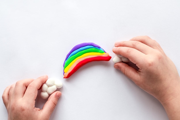 El niño esculpe un arcoíris y nubes de plastilina. La creatividad infantil.