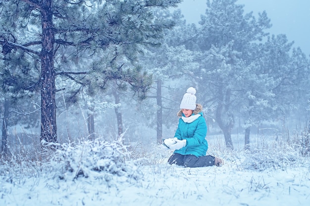 El niño esculpe en el bosque con nieve. La chica de la nieve. Diversión de invierno.