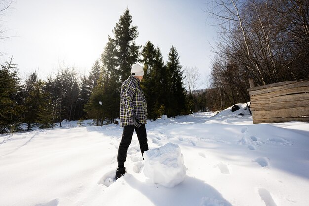 Niño esculpir globo de nieve para muñeco de nieve Juego al aire libre en invierno con nieve en las montañas