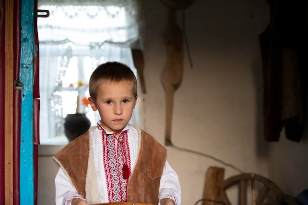 Niño eslavo bielorruso o ucraniano vestido con ropa nacional de fondo rústico