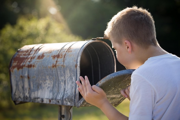 Niño esperando una carta revisando la correspondencia y mirando el buzón de metal