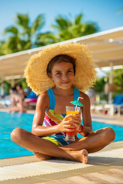 El niño está bebiendo un cóctel junto a la piscina. Enfoque selectivo.